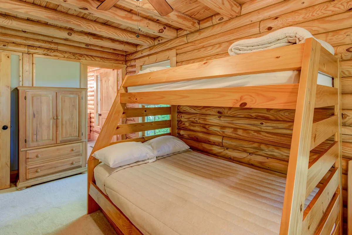 This image showcases a cozy bunk bed room with wooden walls and a wardrobe, perfectly designed for kids to unwind and bond after a busy day. The inviting mood and playful setup evoke memories of laughter and bedtime stories.