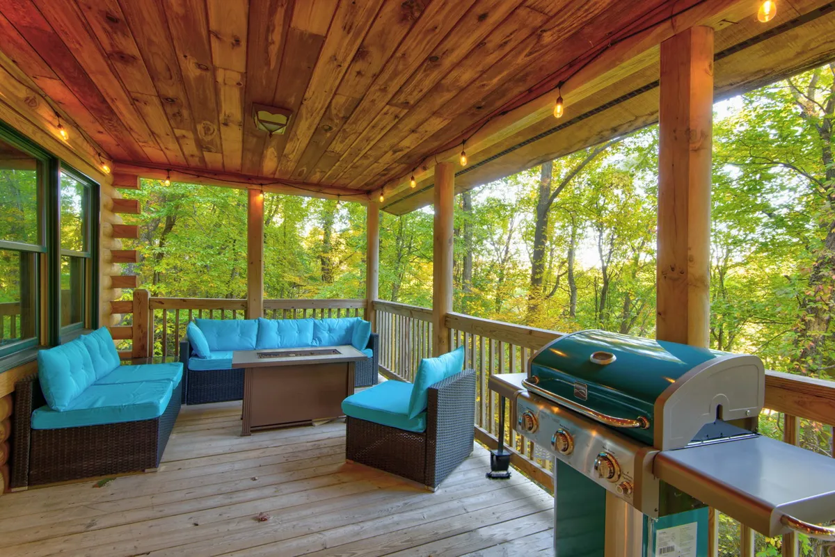 This image showcases an inviting outdoor seating area complete with a grill, wooden ceiling, and comfortable furniture, all surrounded by the lush natural landscape. The space is clearly designed for group gatherings, barbecues, and evening relaxation under the stars.