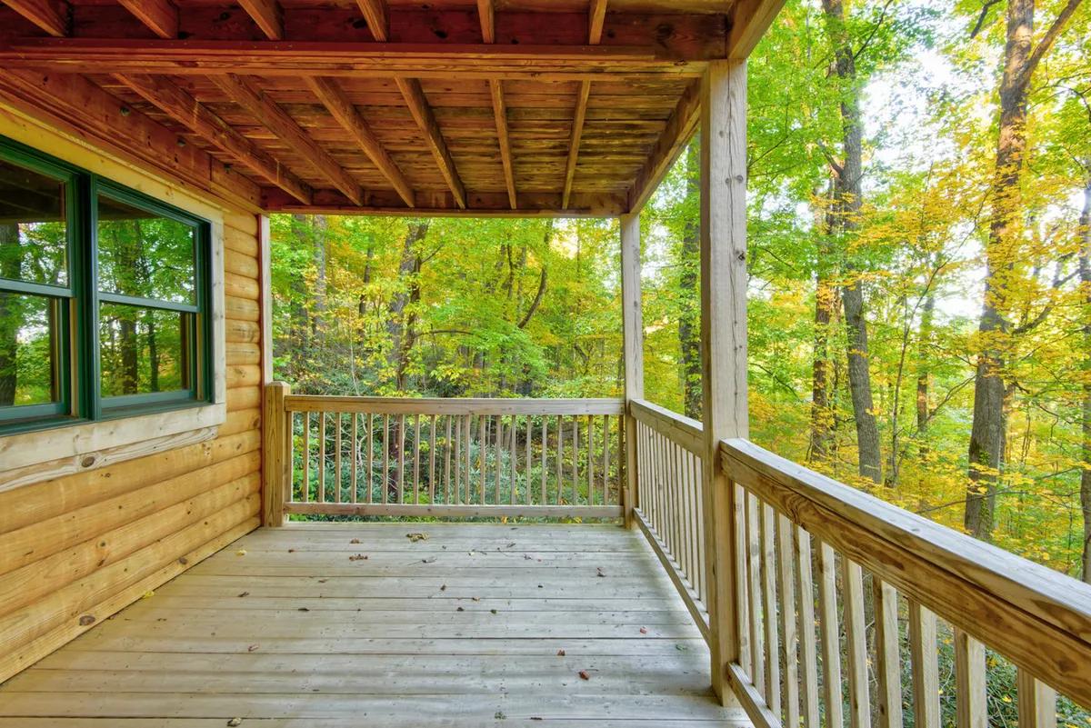 The lower outdoor deck framed by wooden planks and surrounded by trees. Rustic furniture invites guests to relax and cool off after indoor activities, with nature close at hand and plenty of space for fresh air and conversation.