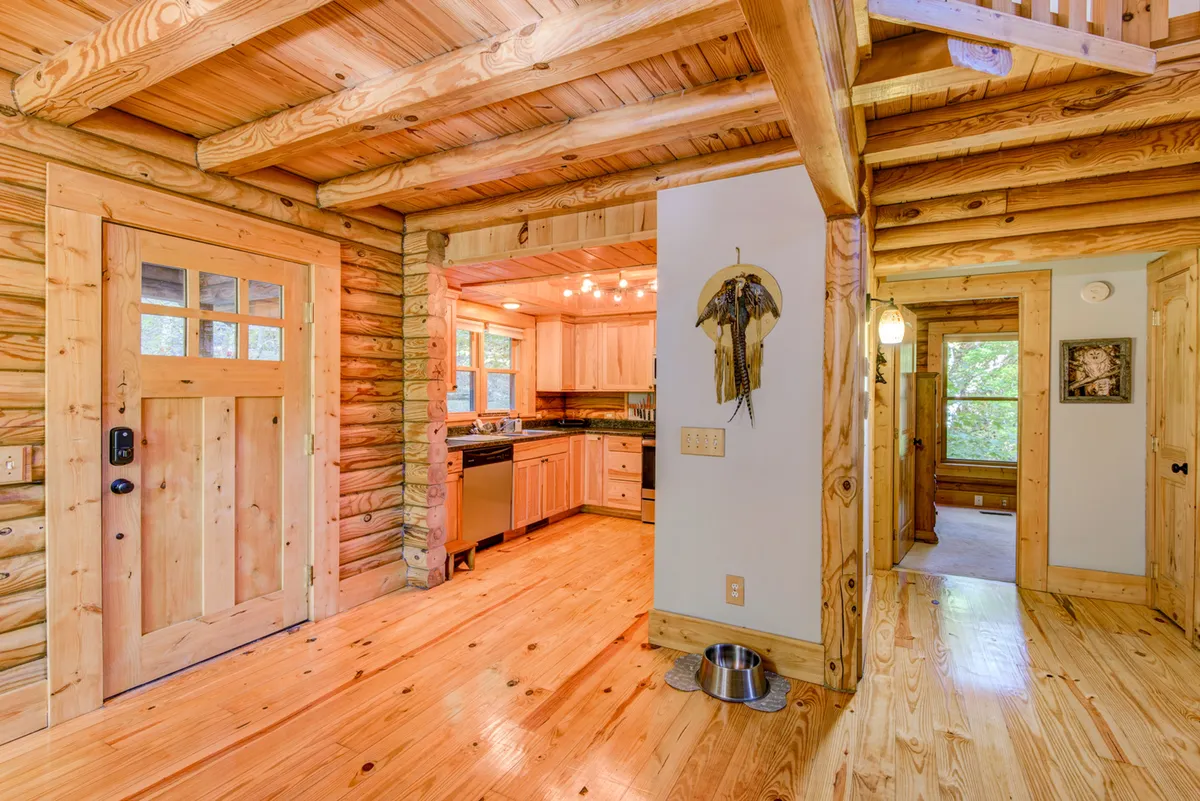 A cozy kitchen and entry area featuring natural wood beams and a visible dog bowl by the door. The kitchen is ready for family gatherings and the scene subtly communicates that pets are welcome and integrated into daily life.