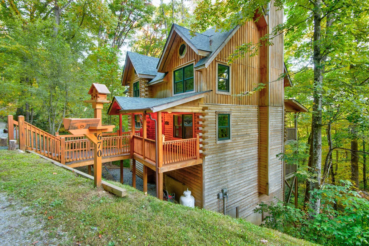 The home's striking exterior with a wooden deck, large windows, and lush trees, inviting guests to connect with nature just steps from the door. The deck is ready for relaxing, enjoying seasonal changes, and outdoor activities with pets.