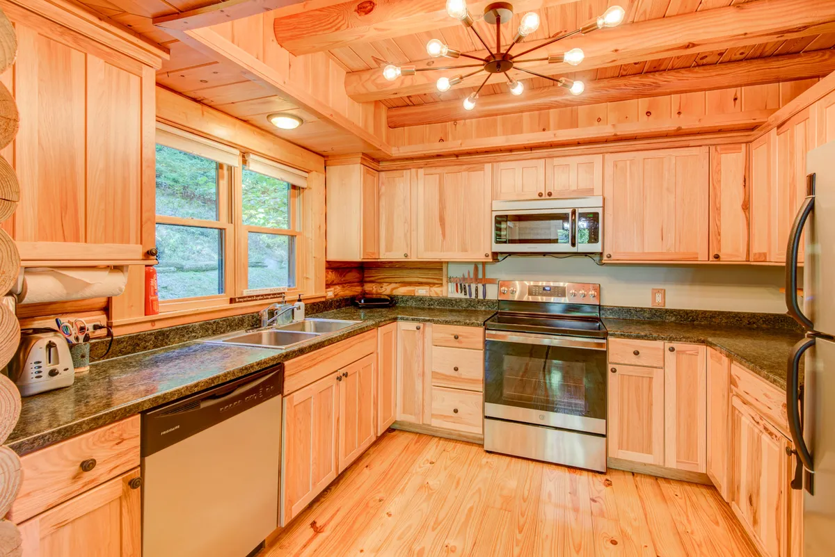A well-equipped kitchen with wooden cabinetry, stainless steel appliances, granite countertops, and large windows. The space radiates a homey atmosphere, perfect for preparing family meals and entertaining guests.